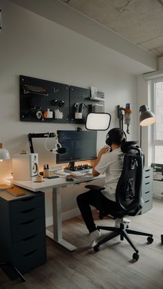 a man sitting at a desk in front of a computer on top of a wooden floor