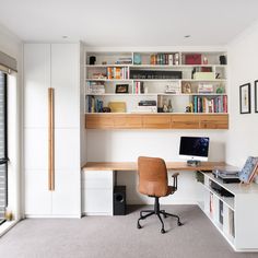 a home office with a desk, bookshelf and large window in the corner