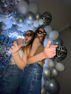 two young women standing next to each other in front of balloons