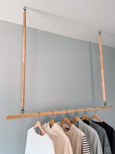 some clothes hanging on a rail in front of a gray wall and two wooden poles