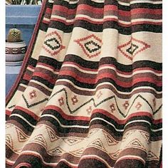 an afghan is displayed on a table next to a potted plant and other decorative items