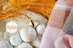 an orange and white bird sitting on top of eggs next to a pile of blankets