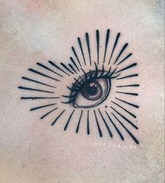 an eye tattoo on the back of a woman's chest with rays coming out of it