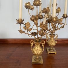 two golden vases with flowers and candles on a table