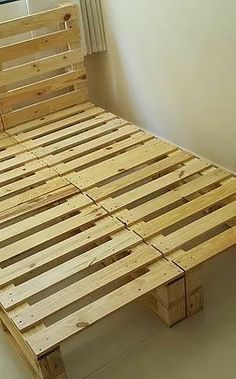 a bed made out of wooden pallets in a room with white walls and tile flooring