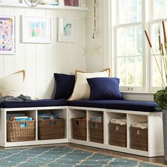 a white bench with blue cushions and baskets on it