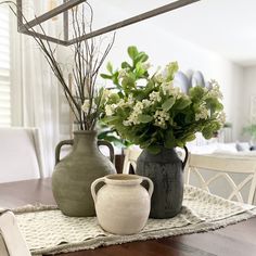 two vases sitting on top of a wooden table next to each other with flowers in them