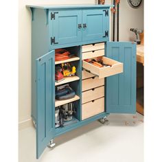 a blue cabinet with drawers and tools in the bottom drawer is open to reveal an assortment of items