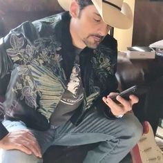 a man wearing a cowboy hat looking at his cell phone