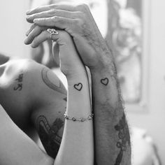 a man and woman with tattoos on their arms holding each other's hands in black and white