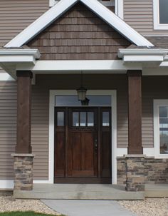 the front entrance to a house with two brown doors and white trim on the windows