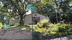 a small house with a street sign in front of it and trees around the corner