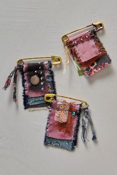 three pieces of fabric hanging from hooks on a white surface, with buttons and tassels attached to them