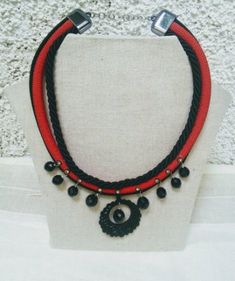 I lately discovered a small shop selling a range of cords and twine that the shopowners produce themselves. They use natural materials like cotton, linen, and plant-based silk. I bought some, and here is the result. A circular necklace with plant-based silk cords in red and black. I used three strands of cord and decorated them with gold and black bindis adorned with small silver crystals. I also added round black beads to the necklace's rim, which are attached using silver metal clasps.  The ce Handmade Black Nylon Cord Jewelry, Handmade Red Jewelry With Nylon Cord, Handmade Black Jewelry With Nylon Cord, Handmade Red Jewelry With Waxed Cord, Silk Cord Necklace, Crochet Bib, Unusual Necklace, Paper Bead Jewelry, Cocktail Jewelry