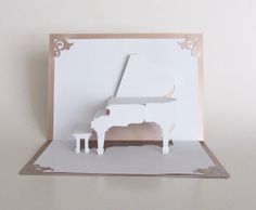 a card with a white piano on top of it, cut out from paper and placed on a wall