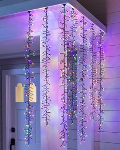 christmas lights are hanging from the side of a house in front of a white door