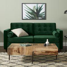 a living room with a green couch and coffee table in front of a painting on the wall