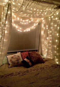 a bed covered in lights and pillows under a canopy