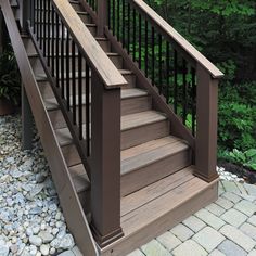 a set of stairs leading up to the top of a wooden deck in front of trees