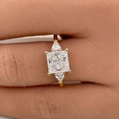 a woman's hand with a diamond ring on top of her finger and an engagement band