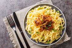 a plate of pasta with meat and parmesan cheese on the side next to a fork