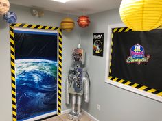 a space themed room with a robot standing in front of the door and some lights hanging from the ceiling