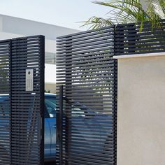 two cars are parked in front of the gated entrance to a building with metal slats on it