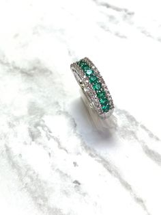 A pretty style she'll love to wear, this fashion ring is a glittering gift of love. Crafted in sterling silver, this band features a row of shimmering lab-created verdant-green emeralds alternating with round-cut lab-created white sapphires. Round sapphire-lined borders flank the top and bottom, adding sparkle to the look. Buffed to a brilliant luster, this beautiful design is sure to be adored. Center stone: Lab Created Emerald Size: 2.5mm Round Side Stones: Lab Grown White Sapphire Size: 1.5mm Fine Jewelry Emerald Stackable Ring For Anniversary, Emerald Cut Stackable Silver Diamond Ring, Emerald Rings With Pave Setting For Anniversary, Anniversary Emerald Rings With Pave Setting, Silver Emerald Stackable Ring With Round Band, Stackable White Gold Emerald Ring In Fine Jewelry Style, Stackable White Gold Emerald Promise Ring, Stackable Open Emerald Ring For Anniversary, Stackable White Gold Emerald Ring Fine Jewelry