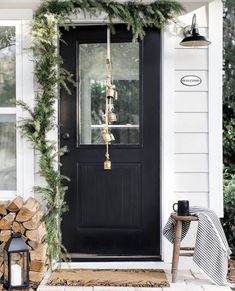 the front door is decorated with evergreen garlands and bells for holiday decor, along with a lantern