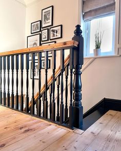 a wooden stair case next to a window with pictures on the wall