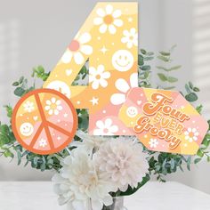 a vase filled with flowers next to a number 4 sign and four stickers on top of it