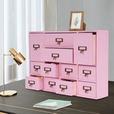 a pink desk with drawers and a lamp