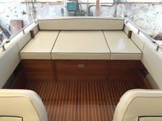 the inside of a boat with white leather seats and wood flooring on it's sides