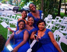 four women in blue dresses posing for the camera at an outdoor event with white chairs