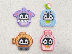 four cross stitched animal magnets sitting on top of a white table next to each other