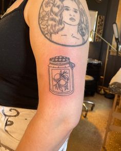 a woman with a tattoo on her arm has a jar of honey in front of her face