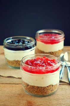 three desserts in small glass jars on a wooden table with spoons and forks