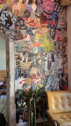 a wall covered in posters and pictures next to a chair with a potted plant