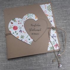 a card with two hearts attached to it on top of a cloth covered tablecloth