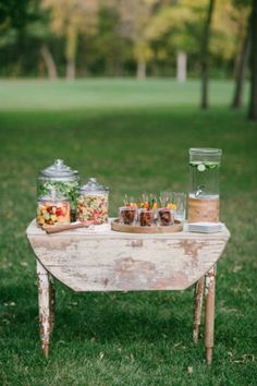 an old table with food on it in the grass