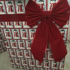 a large red bow on top of a wrapped present box with wrapping paper around it