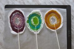 four lollipops with different colors and designs on them sitting on a table