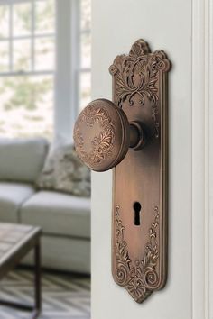 an ornate door handle on the side of a living room with a couch in the background