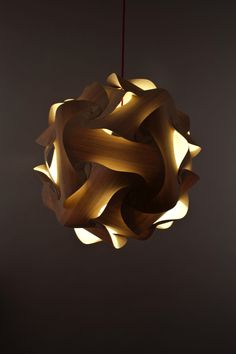 a wooden light fixture hanging from a ceiling in a room with dark walls and flooring