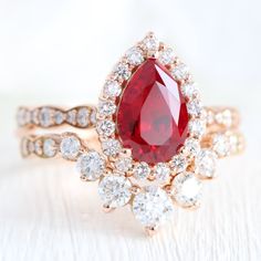 a close up of a ring with a red stone in the middle and white diamonds around it