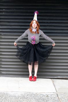 a woman wearing a party hat and black tulle skirt standing in front of a garage door