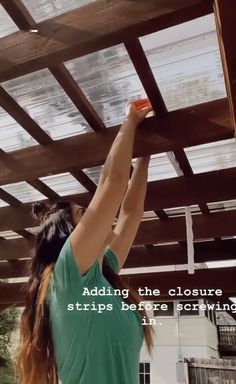 a woman is painting the roof of her house with white paint and she has long brown hair