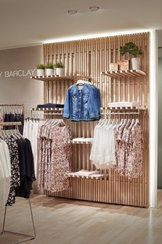 a clothing store display with clothes and jackets on wooden shelvings in front of it