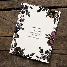 a wedding save the date card on top of a wooden table with flowers and leaves