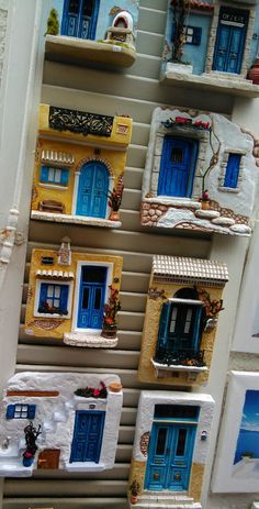 a display of miniature houses with blue doors and windows on the side of a building